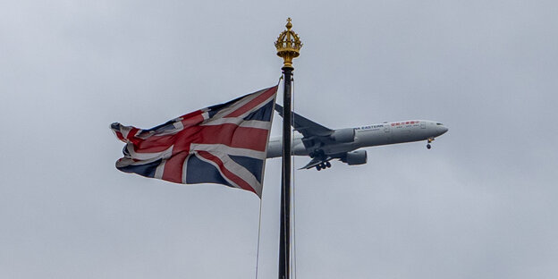 Ein Flugzeug fliegt an einer britischen Flagge vorbei Ein Flugzeug fliegt an einer britischen Flagge vorbei