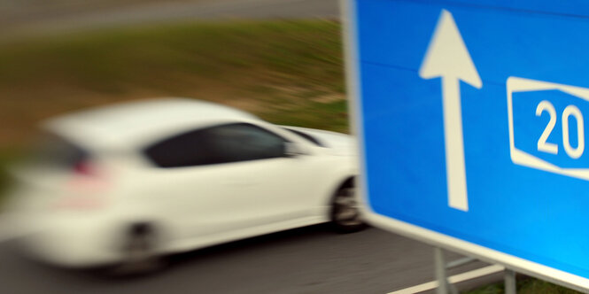 Ein Auto auf einer Landstraße und ein Hinweisschild zur Autobahn 20