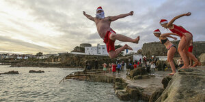 Weihnachtlich verkleidet springen Leute ins Meer an Weihnachten