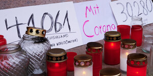 Grablichter und Plakate an einem Gedenkort. «41.061 Corona-Tote in Deutschland», «Mit Corona» und «30.280 Covid-19-Tote» steht auf mehreren Transparenten