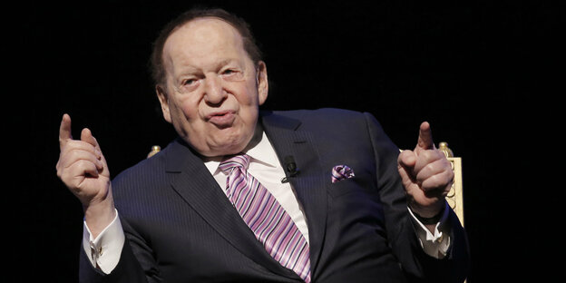 Adelson, im Anzug, gestikuliert mit zwei erhobenen Zeigefingern