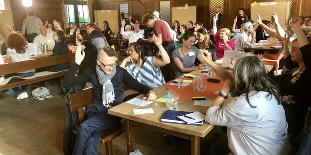 Eine Konferenz von Mehr Demokratie 2019 in einem Münchener Wirtshaus - Menschen heben zu einer Abstimmung die Hand