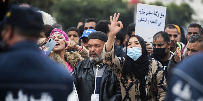 Eine Gruppe von Menschen demonstriert vor einer Absperrung