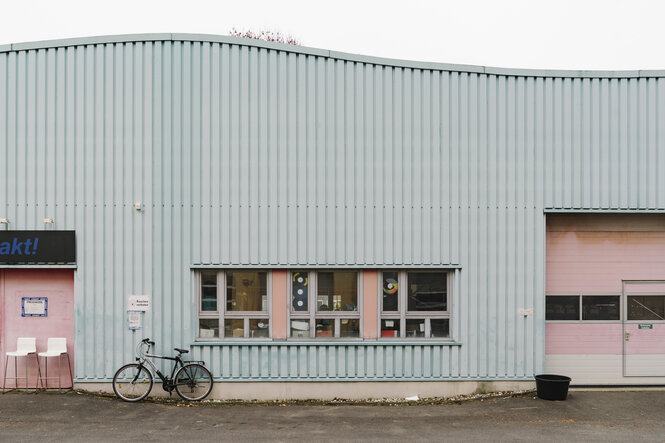 Das Firmengebäude des Vinylpresswerks Intakt im südlichen Teil des Berliner Bezirks Tempelhof ist eine schliche Halle mit gewschwungenem Dach in den Farben Rosa und Hellblau.