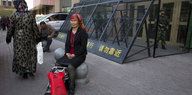 Eine uigurische Frau sitzt vor einem Polizeiposten