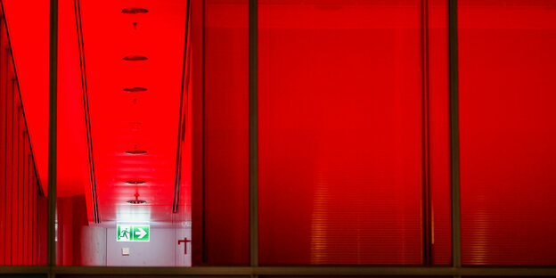 Ein Notausgangsschild hängt in einem farbig beleuchteten Gang in einem Bürogebäude