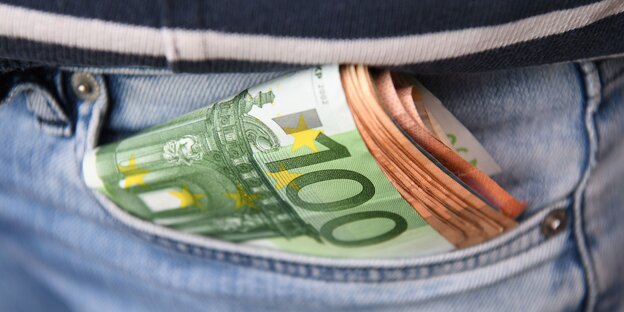 Geldscheinbündel luggt aus einer hinteren Jeanshosentasche hervor