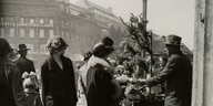 Frauen mit Hut blicken auf einen Verkäuder im Berlin der 20er