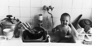 Schwarz-Weiß-Foto eines Babys in einem Küchenspülbecken