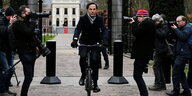 Premierminister Rutte auf einem Fahrrad vor Journalisten.