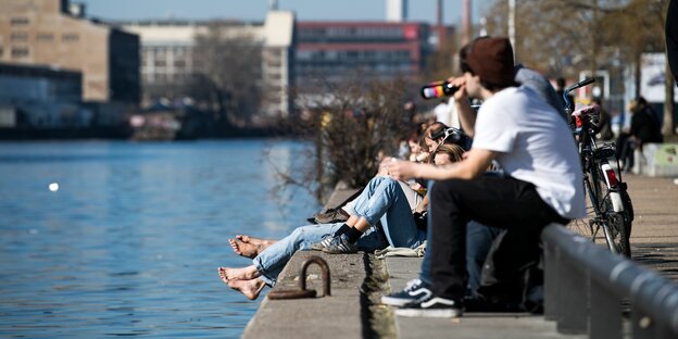 Das Bild zeigt junge Menschen dicht an dicht biertrinkend am Ufer der Spree in Berlin-Friedrichshain