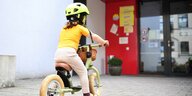 Kind auf Laufrad vor Kita