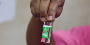 Eine Hand hält eine Impfstoffdosis in der Hand