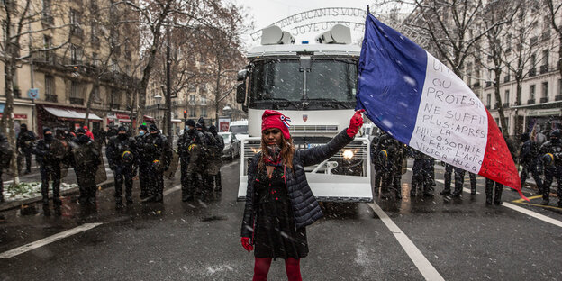 ine Demonstrantin steht in der Pose der Marianne, der Nationalfigur der Französischen Republik, und hält eine französische Fahne,