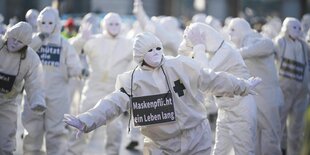 Menschen in Schutzanzügen auf einer Demonstration