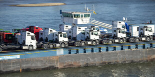 Ein Frachtschiff ist zu sehen, das auf dem Fluss Fahrzeuge transportiert