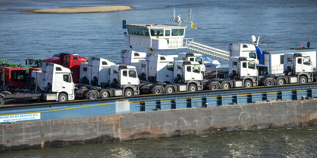 Ein Frachtschiff ist zu sehen, das auf dem Fluss Fahrzeuge transportiert