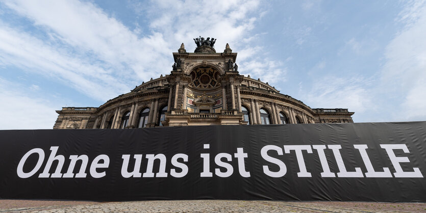 Semper-Oper mit schwarzen Transparent davor und blauem Himmel