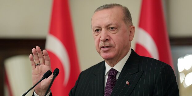 Der türkische Präsident Erdogan mit erhobener Hand vor einem Mikrofon