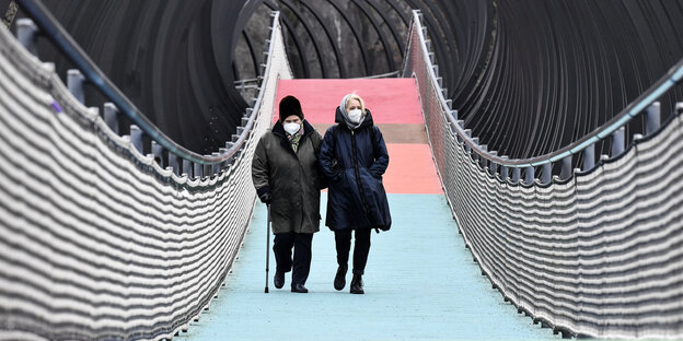 Zwei Frauen mit FFP2 Masken gehn über eine Brücke