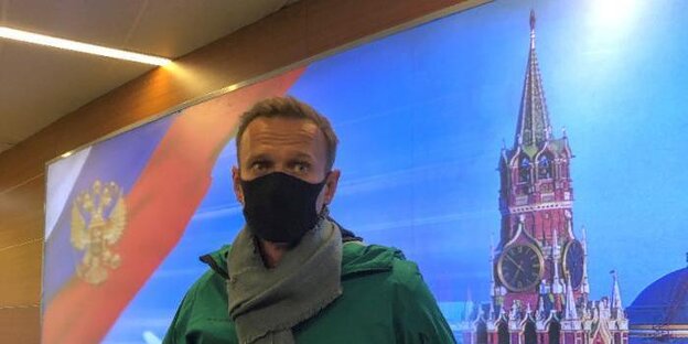 Nawalny mit Mundschutz, im Hintergrund ein Foto des Moskauer Kreml