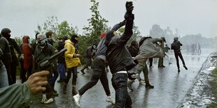 Vermummte Demonstranten werfen mit Steinen.