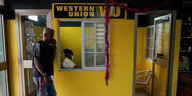 Knallgelbes Büro der Western Union , davor ein Mann am Telefon