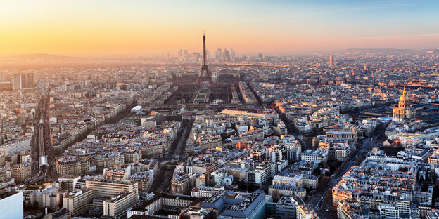 Eine Luftaufnahme zeigt die Innenstadt von Paris mit Eiffelturm vor der untergehenden Sonne