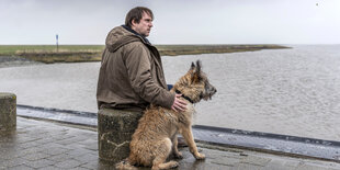 Bjarne Mädel mit Hund Cord vor Wattenmeer.