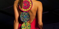 Die Rückenansicht einer Frau mit drei Scheiben in bunten Motiven, die ihr Kleid hinten verbinden