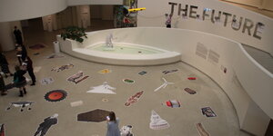 Besucher in der berühmten Spirale des Guggenheim Museums. der Fußboden ist mit Ausschneidefiguren, Kühen, Menschen, Windrädern, Buddhas etc. beklebt