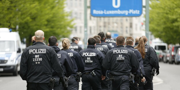 Mehrere Berliner Polizisten laufen in Richtung U-Bahn Station Rosa Luxemburg Platz