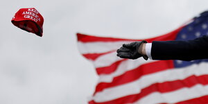 Noch-Präsident Donald Trumps lederbehandschute Hand wirft Keep America Great-Käppi in die L