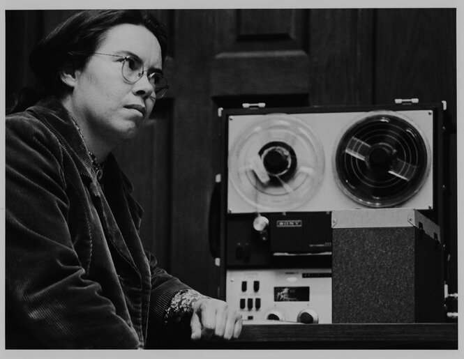 Die Komponistin Pauline Oliveros sitzt an einem Tonbandgerät.