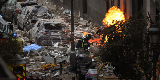 Feuerwehrleute arbeiten neben einem beschädigten Gebäude nach einer Explosion