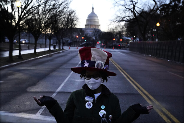 Eine Frau mit US-Flaggenhut und Puppen von Biden und Harris im Revers posiert auf der Straße vor dem Kapitol