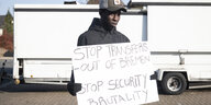 Vor der Erstaufnahmestelle Lindenstraße in Bremen protestiert ein Mann gegen die Unterbringung. Auf seinem Schild steht "Stop Transfers out of Bremen" (Stoppt Transfers aus Bremen) und "Stop Security Brutality" (also: Stoppt die Brutalität der Security)