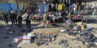 Menschen und Sicherheitskräfte am Anschlagsort - ein verwüsteter Markt mit Kleidungsstücken verstreut auf dem Boden