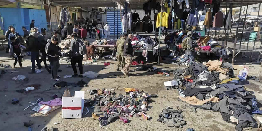 Menschen und Sicherheitskräfte am Anschlagsort - ein verwüsteter Markt mit Kleidungsstücken verstreut auf dem Boden