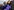 Kamala Harris im violetten Mantel, mit Maske und Handschuhen winkt in die Kamera