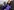 Kamala Harris im violetten Mantel, mit Maske und Handschuhen winkt in die Kamera
