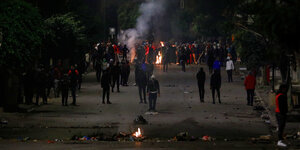 Junge Demonstranten in einer Strasse, ein kleines Feuer brennt