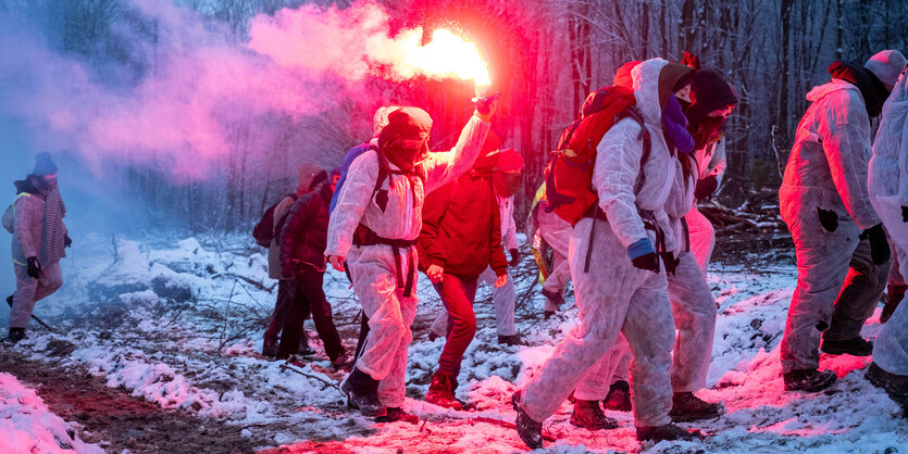 Menschen in Schutzbekleidung laufen durch einen Wald