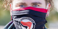 Mensch mit Gesichtsmaske, darauf das Logo der Antifaschistischen Aktion