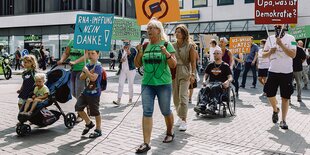 Carola Javid-Kistel geht mit einem Demonstrationszug mit und spricht in ein Mikro.