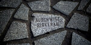 Stein mit Inschrift "Auschwitz Birkenau" am Denkmal und Mahnmal für die im Nationalsozialismus ermordeten Sinti und Roma Europas gegenüber dem Reichstagsgebäude in Berlin.