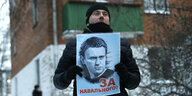 Eine Mann hält ein großes Foto von Alexei Nawalny