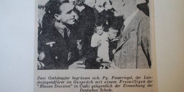 Ein alter Zeitungsausschnitt mit dem Vater. Die Bildunterschrift lautet: Zwei Ostkämpfer begrüssen sich. Pg. Feuerriegel, der Landesjugendführer im Gespräch mit einem Freiwilligen der "Blauen Division" in Cadiz.