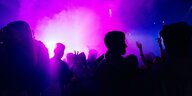 Menschen tanzen, der dunkle Raum ist mit lila Scheinwerfern bestrahlt