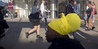 Eine Frau mit einer gelben Kopfbedeckung steht auf der London Bridge zwischen Fußgängern
